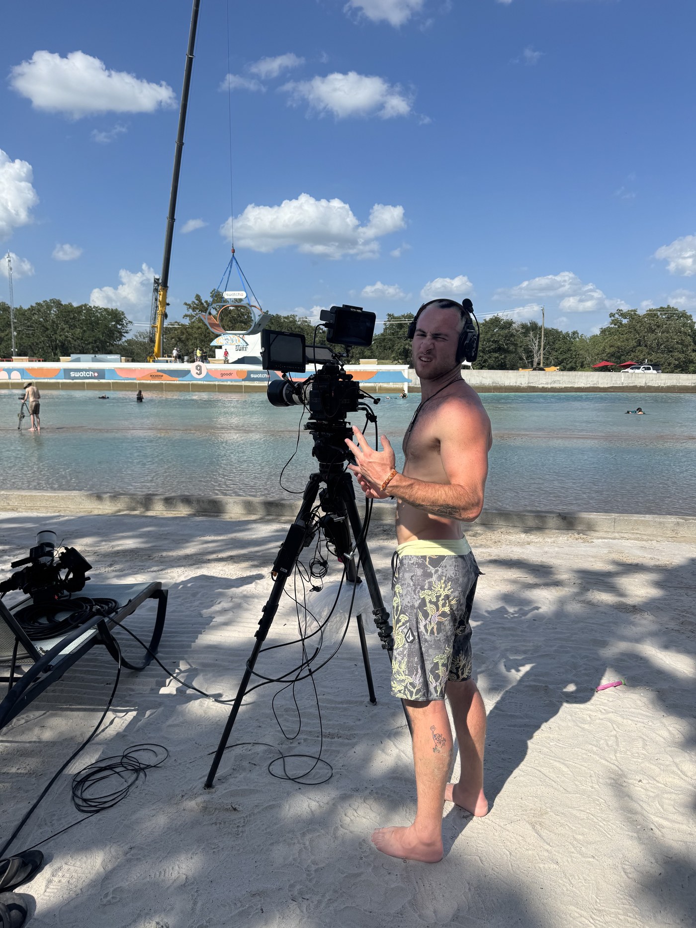 Kole beside a cinema camera on a tripod at a wave park