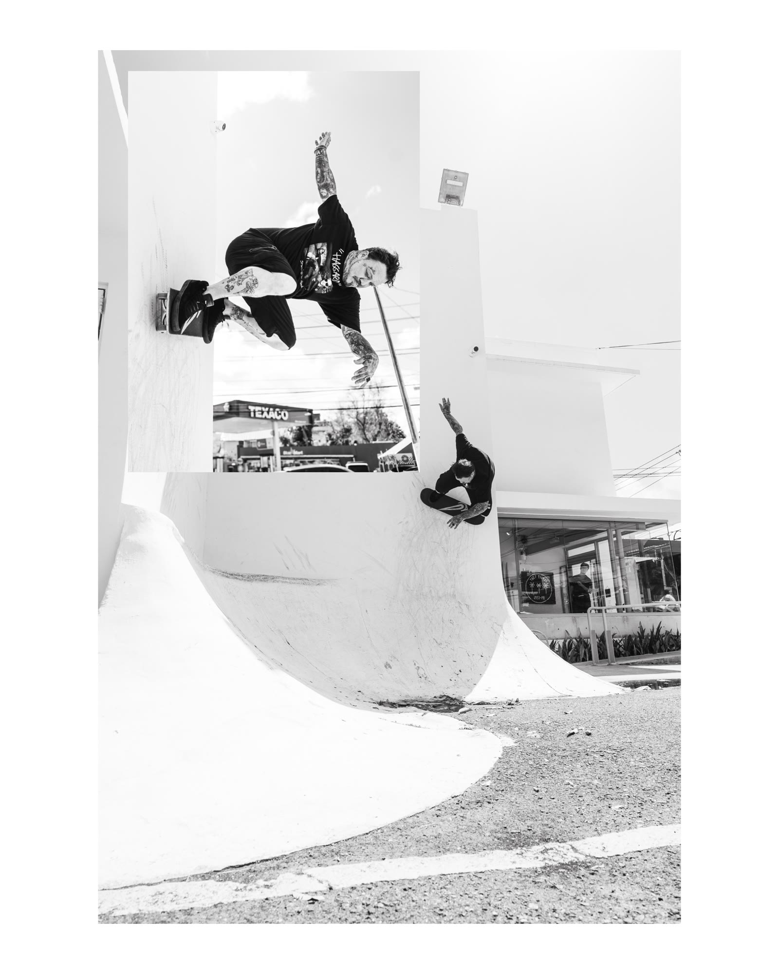 Black and white photograph of a skater riding a bank beside a Texaco station
